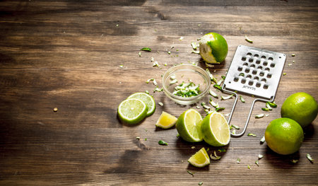 Fresh limes with grater and zest. On a wooden table.の写真素材
