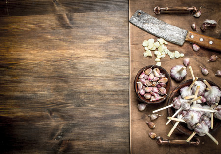Sliced garlic cloves with an old knife. On a wooden table.の写真素材