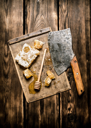 Sweet honey in the comb with an old hatchet. On wooden background.の写真素材
