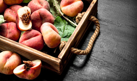 Ripe peaches in a wooden box. On the black chalkboard.の写真素材