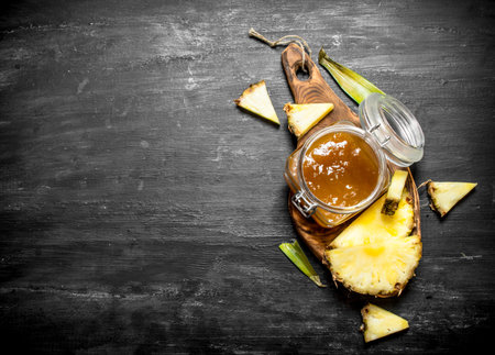 Pineapple jam in a jar. On a black wooden background.の写真素材
