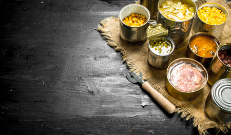 Different canned products in tin cans. On the black chalkboard.の写真素材
