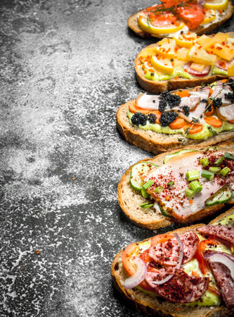 Sandwiches with meat, salami, seafood and fresh vegetables. On a rustic background.の写真素材