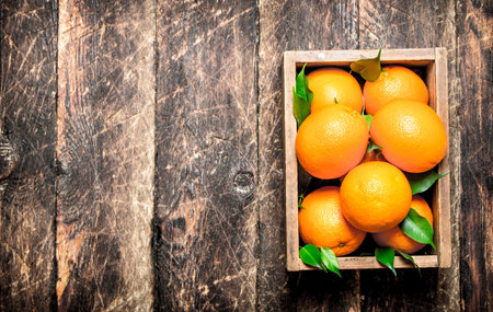 Fresh oranges in an old box. On wooden background.の写真素材