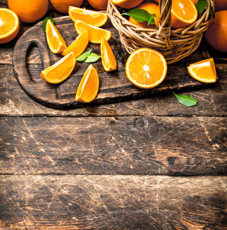 Sliced pieces of oranges in the basket. On wooden background.の写真素材