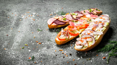 Sandwiches with meat, salami, seafood and fresh vegetables. On a rustic background.の写真素材