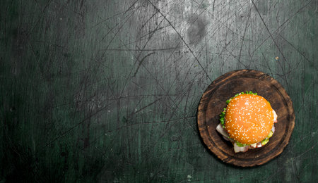 Fresh burger with beef, bacon and fresh vegetables. On a rustic background.の写真素材