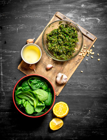 Pesto sauce with olive oil, garlic and other ingredients. On the black wooden table.の写真素材
