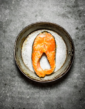 piece of fried salmon on the old pan. On the stone table.