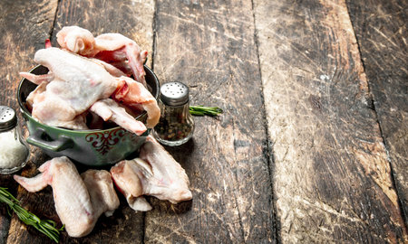 Raw chicken wings with spices and herbs. On a wooden table.の写真素材