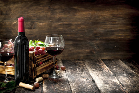 Wine background. Red wine with a box of grapes. On a wooden background.の写真素材