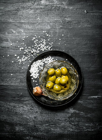 Olives in oil and salt. On a black rustic background.の写真素材