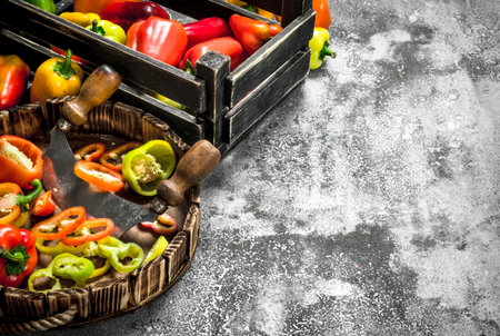 chopped sweet pepper in a wooden tray with a knife. On a rustic background.の写真素材