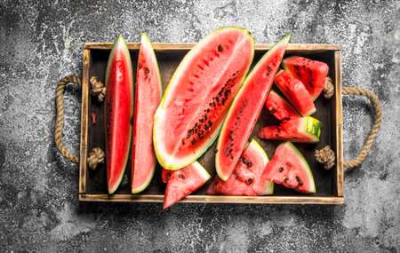 Sliced ripe watermelon on a wooden tray. On a rustic background.の写真素材