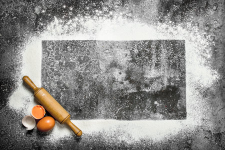 Baking background. A frame of flour with a rolling pin and fresh eggs. On a rustic background.の写真素材