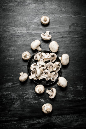 Sliced mushrooms in the pan. On black rustic background.の写真素材