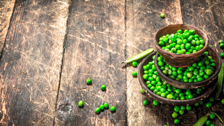 Fresh green peas in a bowl. On a wooden background.の写真素材