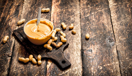 Peanut butter with nuts. On wooden background.