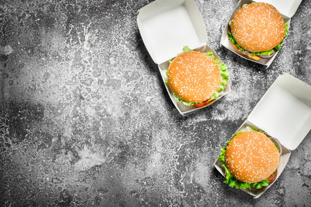 Fresh burgers in paper boxes. On a rustic background.の写真素材