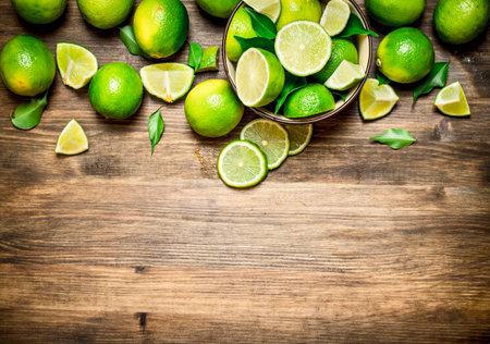 Ripe limes in a bowl. On a wooden table.の写真素材