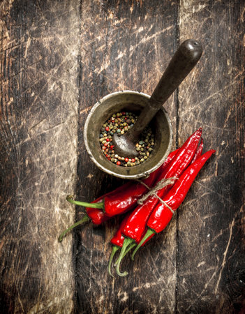 Hot chili peppers with a mortar. On a wooden background.の写真素材