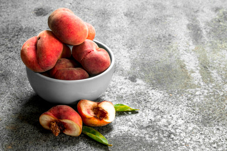 Fresh peaches in a bowl . On a rustic background.の写真素材