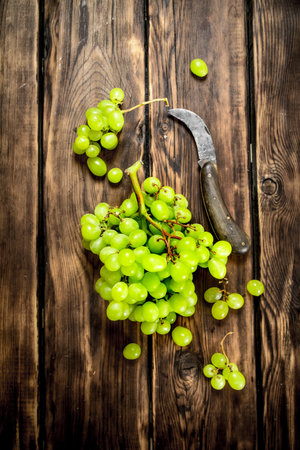 White grapes with an old knife. On a wooden table.の写真素材