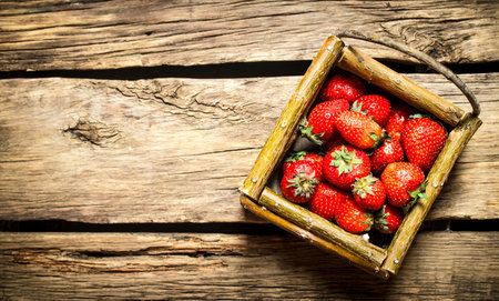 Strawberries in a basket. On the wooden table.の写真素材