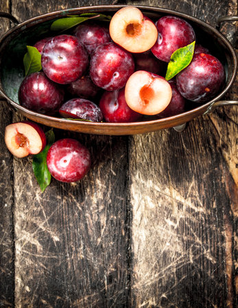 Fresh plums in a bowl. On a wooden background.の写真素材