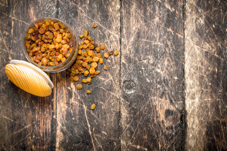 Raisins in a bowl. On wooden background.の写真素材