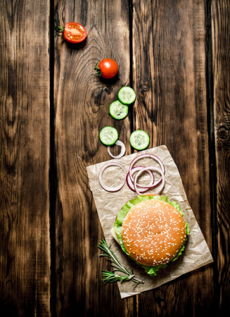 Cooked Burger with vegetables, cheese and meat. On wooden background. Top view.の写真素材