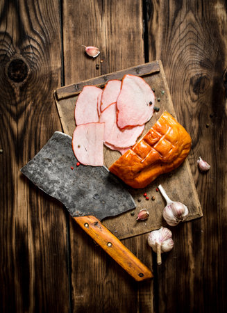 Ham with a hatchet and garlic on the Board. On wooden background.の写真素材