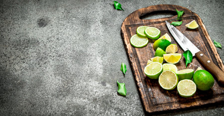 Sliced fresh limes on a cutting Board with a knife . On rustic background.の写真素材
