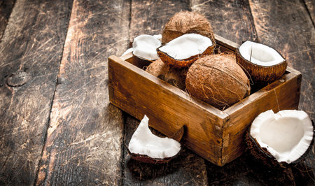 Fresh coconuts in an old box. On a wooden table.
