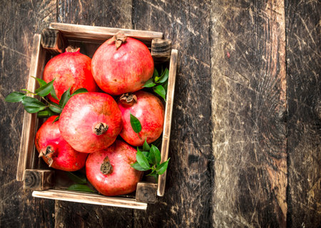 Fresh pomegranates in an old box. On a wooden background.の写真素材
