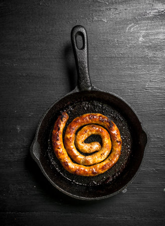 Sausage in the pan. On the black chalkboard.の写真素材