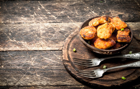 Chicken nuggets in a bowl with forks. On a wooden background.の写真素材