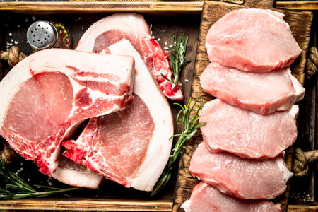 Raw pork meat with herbs and spices in a tray. On rustic background.の写真素材