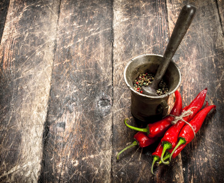 Hot chili peppers with a mortar. On a wooden background.の写真素材
