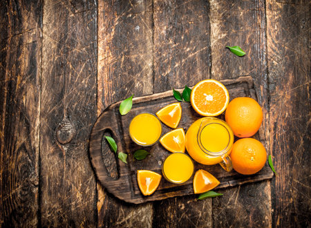 Fresh juice from ripe oranges. On wooden background.の写真素材