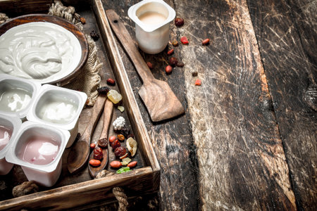 Fresh yoghurt with dried fruits on a tray. On a wooden background.の写真素材