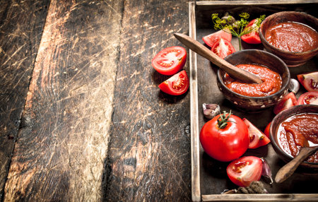 Tomato sauce with spices and garlic in the old tray. On wooden background.の写真素材