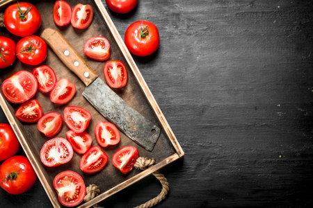 Tomatoes with old hatchet on the tray. On black chalkboard.の写真素材