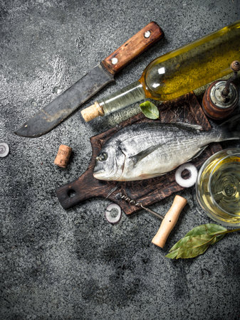 Fresh unprepared Dorado fish with white wine. On a rustic background.の写真素材