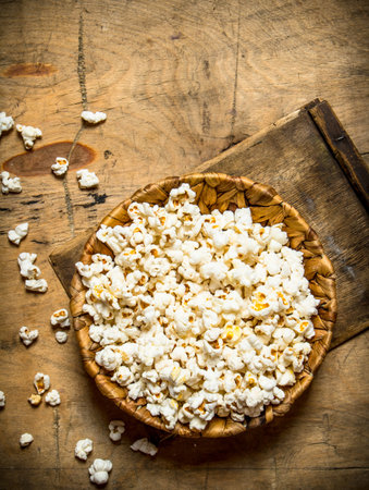 The popcorn in the bowl. On a wooden table.の写真素材