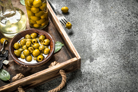 Olive oil with pickled olives on an old tray. On a rustic background.の写真素材