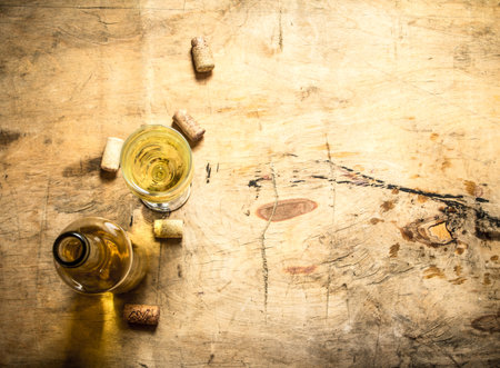 White wine with a corkscrew and stoppers. On wooden background.の写真素材