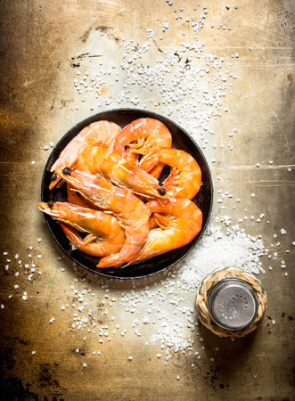 Frying pan with shrimp and salt. On an old rustic background .の写真素材