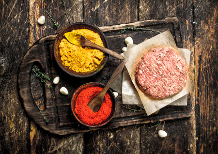 Raw burger with spices and herbs. On a wooden background.の写真素材