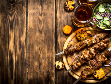Pork kebab with beer and vegetables. On wooden background.の写真素材